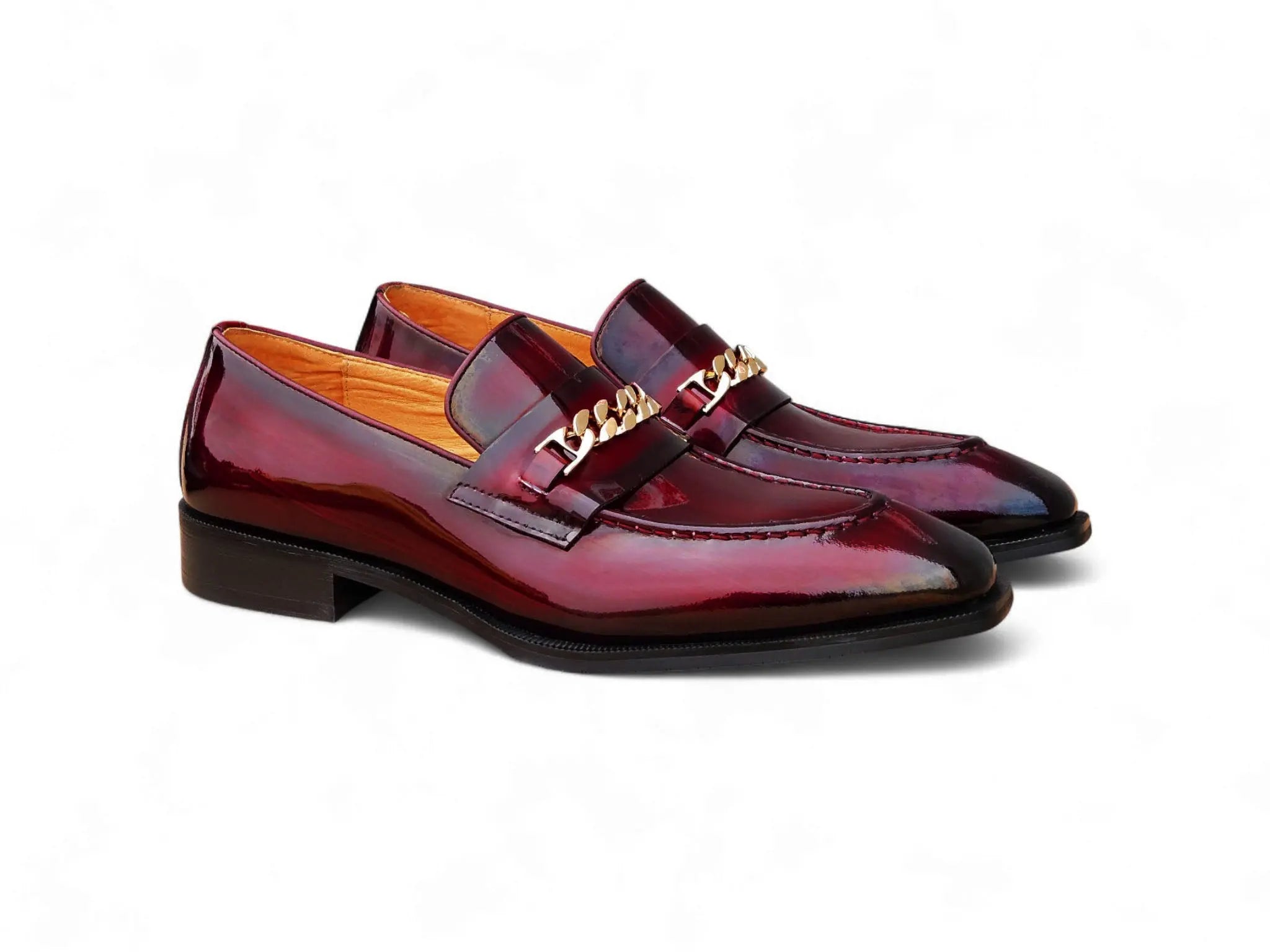 Shiny red loafers with gold accents on a white background